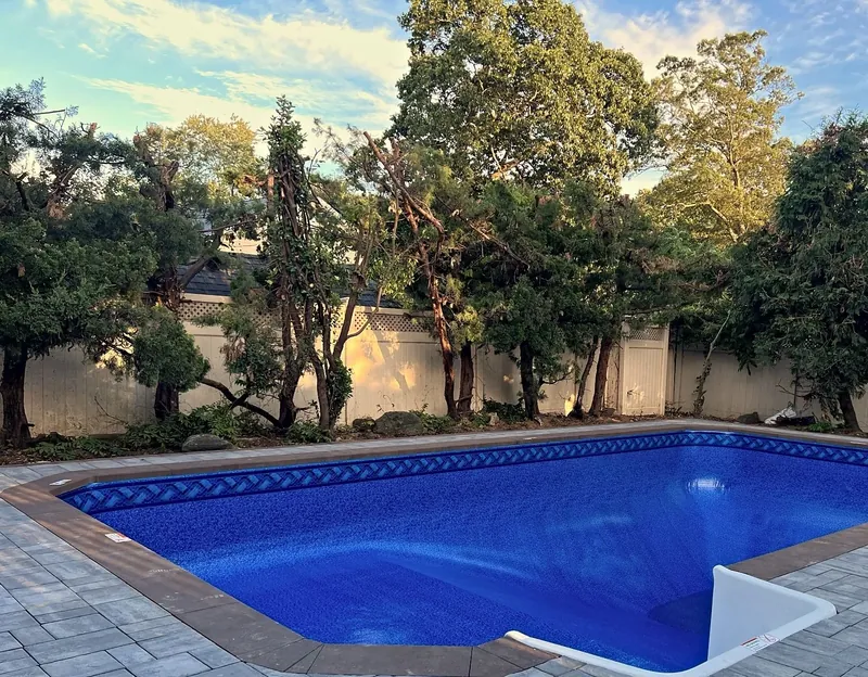 Finished pool with braided-border liner, brown coping and paver patio