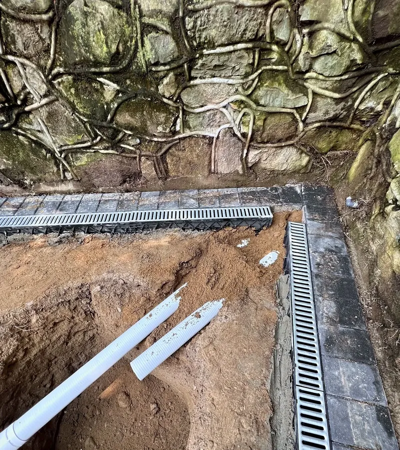 Stormwater Drainage & Dry Wells – Linear channel drains along the retaining wall, piped to a dry well