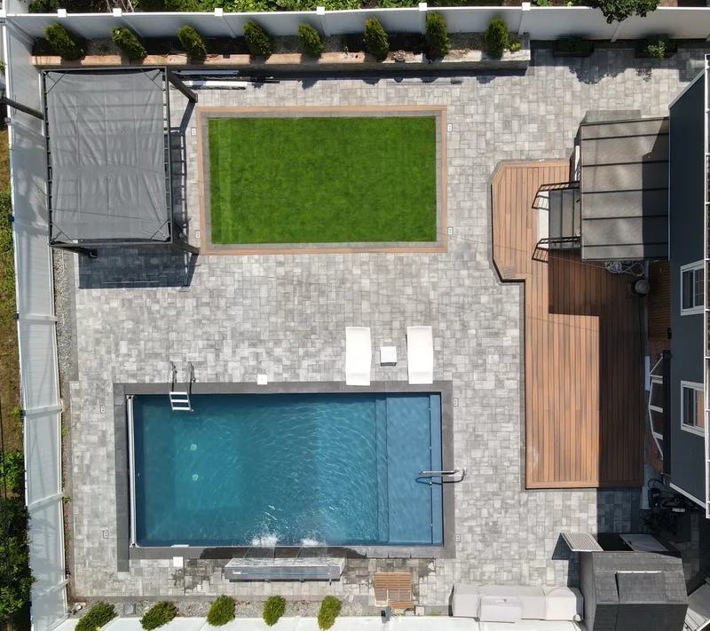 The whole lot from above: pool and waterfall, paver field, turf panel, pergola, composite deck, outdoor kitchen and perimeter fence